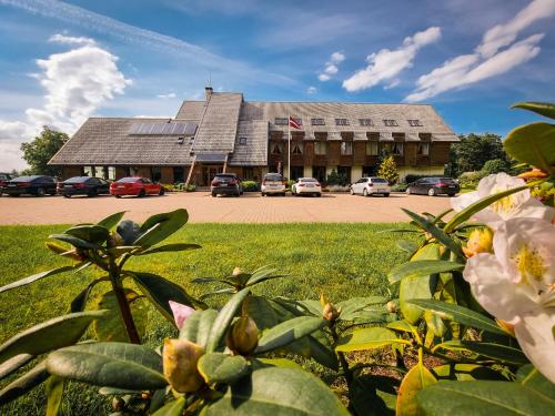 a large building with cars parked in a parking lot at Abzali Hotel and Restaurant with self check-in in Ādaži