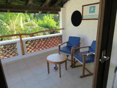 a room with two chairs and a table on a balcony at Pinewood Beach Resort and Spa in Diani Beach