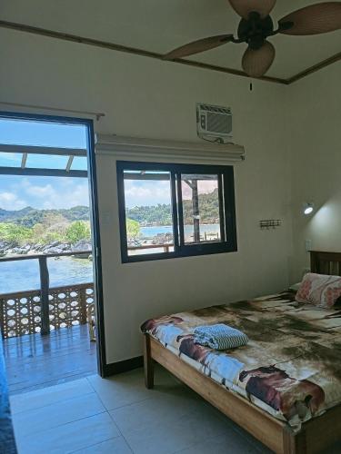 a bedroom with a bed and a large window at El Gordo's Seaside Adventure Lodge in El Nido