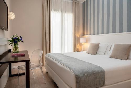 a hotel room with a bed and a table and a desk at Hotel Villa Rosa Riviera in Rimini