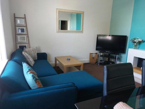 a living room with a blue couch and a tv at Lovely 2 bedroomed flat in the centre of Longton in Longton