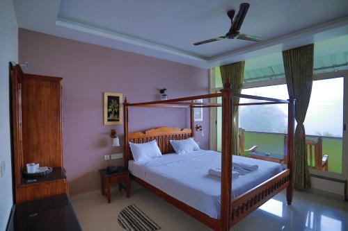 a bedroom with a canopy bed and a window at Green Valley Vista in Munnar