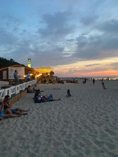 a group of people sitting on the beach at sunset at VIlla Mare Apartamenty in Pobierowo