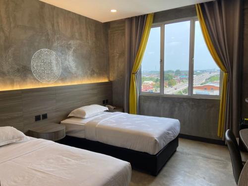 a hotel room with two beds and a window at Sri Indar Hotel & Suites in Parit Buntar