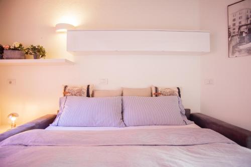 Una cama con almohadas moradas en un dormitorio en BnButler - Alfieri, 15 - Vecchie Atmosfere, en Milán
