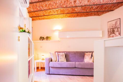 sala de estar con sofá púrpura y mesa en BnButler - Alfieri, 15 - Vecchie Atmosfere, en Milán
