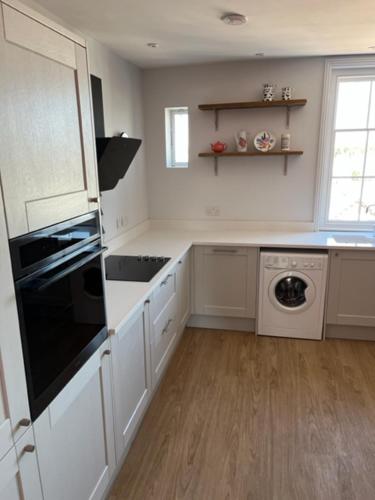 una cocina con armarios blancos y un aparato negro en Aspen-free parking-Grade II listed-second floor two bedrooms apartment en Huntingdon