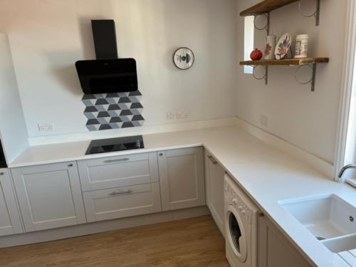 a kitchen with white cabinets and a stove top oven at Aspen-free parking-Grade II listed-second floor two bedrooms apartment in Huntingdon