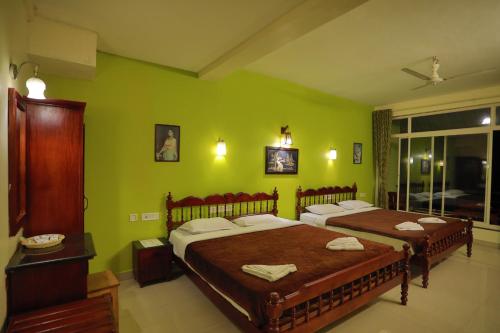 two beds in a room with green walls at Green Valley Vista in Munnar