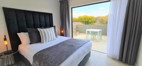 um quarto com uma cama grande e vista para um pátio em MINT Apartments Greenside em Joanesburgo