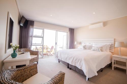 Un dormitorio con una gran cama blanca y sillas en Finchley Guesthouse, en Ciudad del Cabo