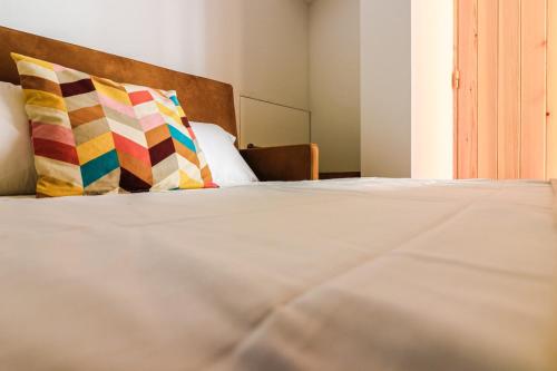 Una cama con dos almohadas coloridas. en Refúgio da Fortaleza, en Sesimbra