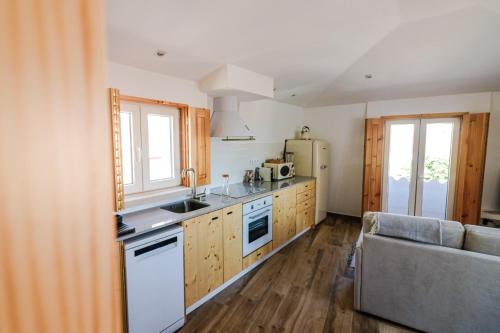 a kitchen with wooden cabinets and a couch in a room at Refúgio da Fortaleza in Sesimbra