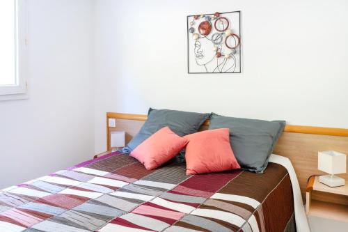 a bedroom with a bed with two pink pillows at Appartement La Coline Bleue in Biarritz