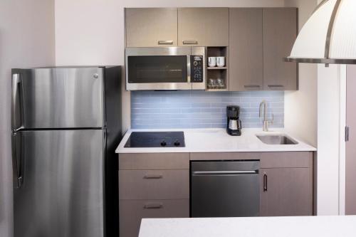 a kitchen with a stainless steel refrigerator and a sink at Hyatt House Tallahassee Capitol University in Tallahassee