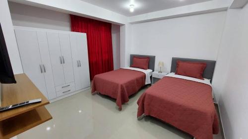 a bedroom with two beds and a red curtain at Departamentos amoblados en Huánuco in Huánuco