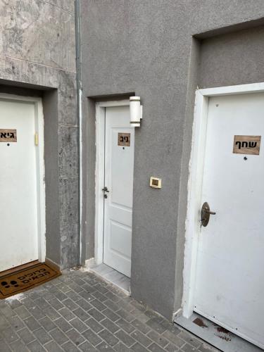 גיא ברוזמרין في إيلات: ثلاثة أبواب بيضاء على جانب المبنى