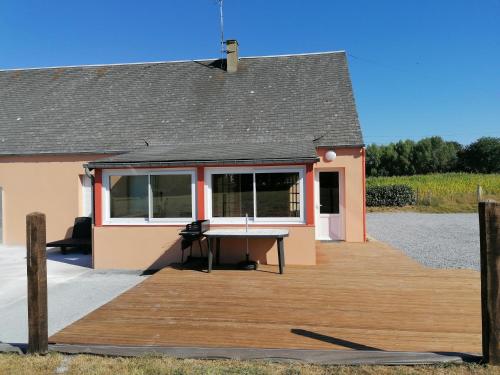 une maison avec une terrasse en bois devant elle dans l'établissement Gite de la Courtoisie, à Gavray