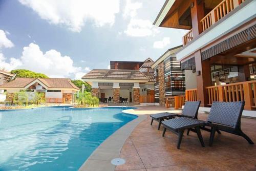 una piscina con due sedie accanto a una casa di Dreamy 2BR condo, with a golf course view a Cebu City