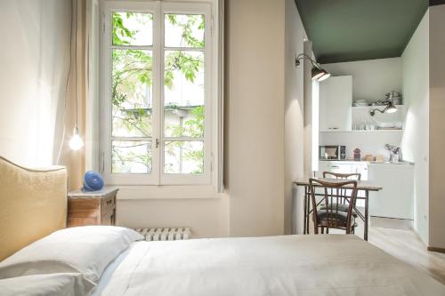 Schlafzimmer mit einem Bett, einem Tisch und einem Fenster in der Unterkunft Brera Apartments in Porta Romana in Mailand