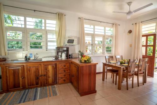 a kitchen with wooden cabinets and a table and chairs at La Maison Hibiscus Self Catering Accommodation in Beau Vallon