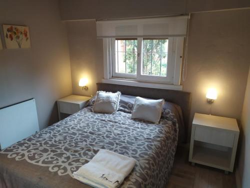 a bedroom with a bed with two pillows and a window at Tierra Mora Casas de alquiler, ESTA PROPIEDAD SE GESTIONA SOLO POR ESTA PAGINA, SOLO GRUPOS FAMILIARES in Villa Gesell