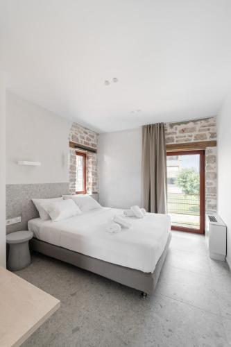 a white bedroom with a large bed and a window at Kampus Luxury Villas in Tríkala