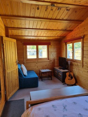 Cabaña de madera con cama, TV y guitarra en The Lodge, en Sidlesham