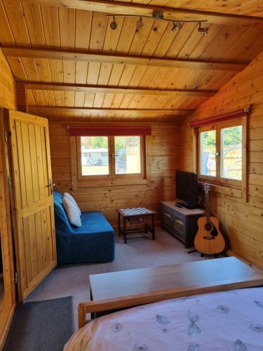 a log cabin with a bed and a tv and a guitar at The Lodge in Sidlesham