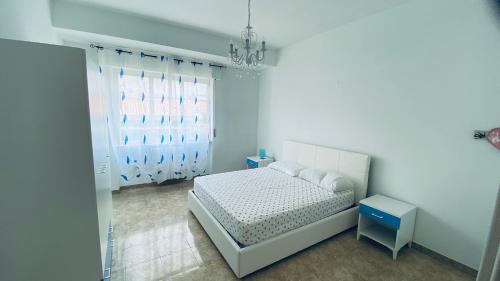 a white bedroom with a bed and a chandelier at Oasi Home in Sulmona