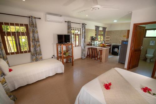 a living room with two beds and a kitchen at La Maison Hibiscus Self Catering Accommodation in Beau Vallon