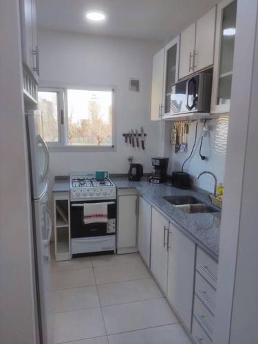 a white kitchen with a stove and a sink at Departamento Tigre luminoso frente a club Hacoaj in Tigre