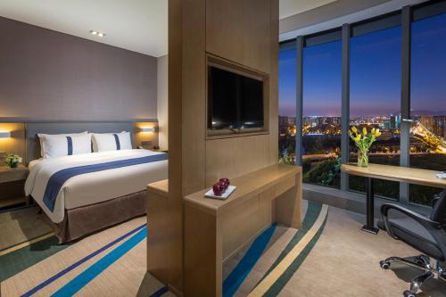 a hotel room with a bed and a large window at Holiday Inn Express Hangzhou East Station by IHG in Hangzhou