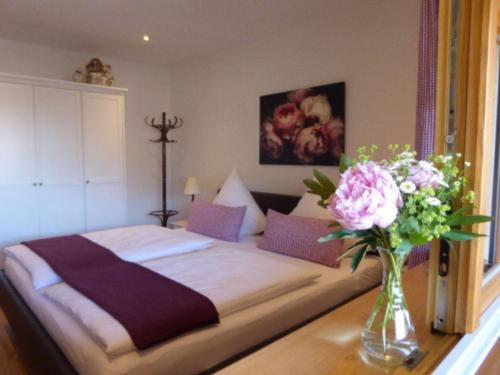 - une chambre avec un lit et un vase de fleurs sur une table dans l'établissement Ferienwohnung Schreiner-Viehhausen, à Grassau