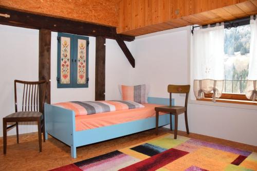 a bedroom with a bed and a chair and a window at Landhaus Pitztal inklusive Sommercard in Jerzens