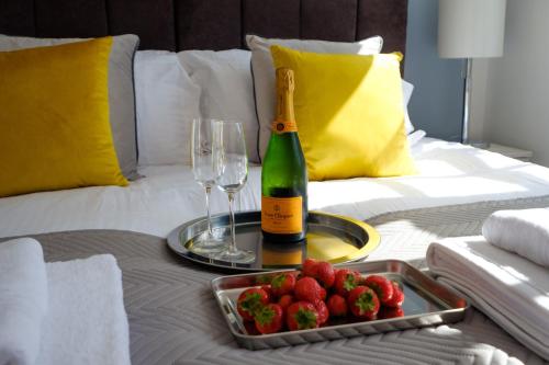 a bottle of champagne and a tray of strawberries on a bed at Riverwalk Apartment One in Datchet