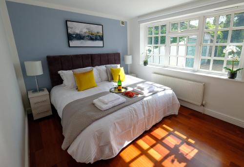 a bedroom with a large bed with yellow pillows at Riverwalk Apartment One in Datchet