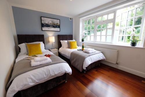 two beds in a room with two windows at Riverwalk Apartment One in Datchet
