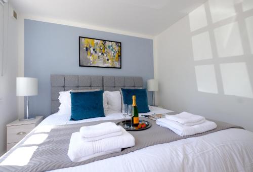 a bedroom with a large white bed with blue pillows at Riverwalk Apartment One in Datchet