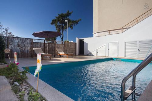 a swimming pool with an umbrella next to a house at Apartments Villa Dinka in Opatija