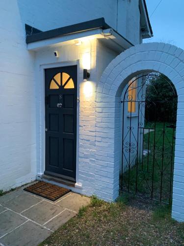 a white brick house with a black door at Riverwalk Apartment One in Datchet