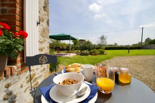 - une table avec un bol de céréales et un bol de jus d'orange dans l'établissement O Trois Oliviers, à Louin