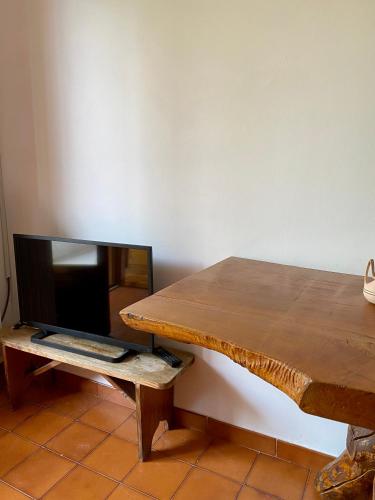 a wooden table with a tv and a wooden bench at Casa Uliveto in Mattinata