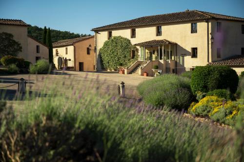 a house with a yard with grass and flowers at La Bagnaia Golf Resort in Bagnaia