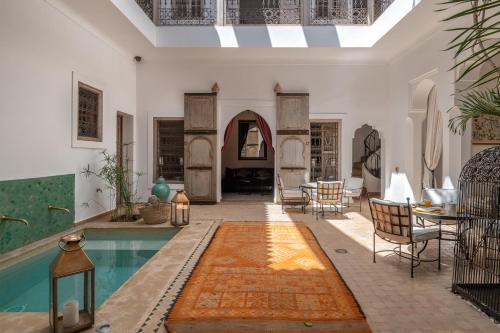 a living room with a pool and a table and chairs at Riad Altair in Marrakesh