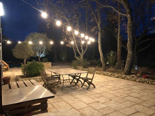 eine Terrasse mit einem Tisch und Stühlen in der Nacht in der Unterkunft Chambre d’hôtes l’Orange Bleue in Rustrel