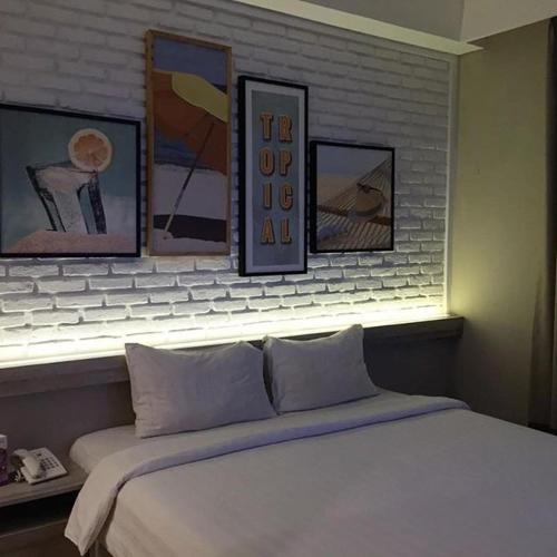 a bedroom with a white bed with pictures on the wall at Expressia Hotel Makassar in Makassar