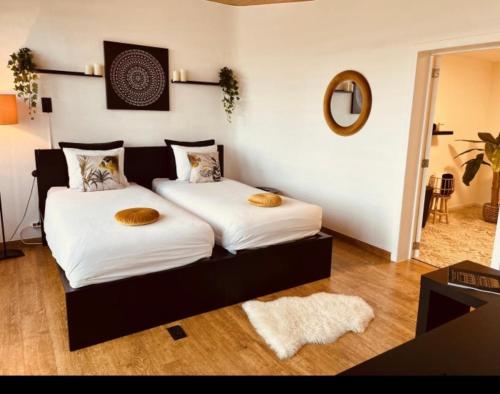 1 dormitorio con 2 camas con sábanas blancas y espejo en La Villa Bastogne chambre d'hôtes 1 en Bastogne