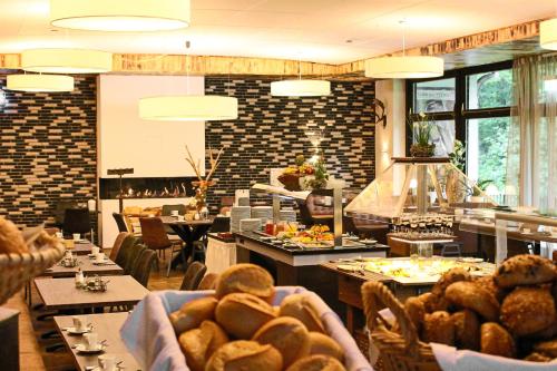 a restaurant with tables and chairs with food on them at Forsthaus-Ferienhotel am Dobrock in Wingst