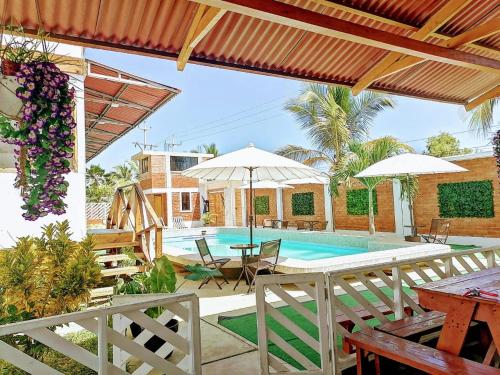 un patio con piscina, tavoli e ombrelloni di Hospedaje PILARES DE BOCAPAN a Bocapán